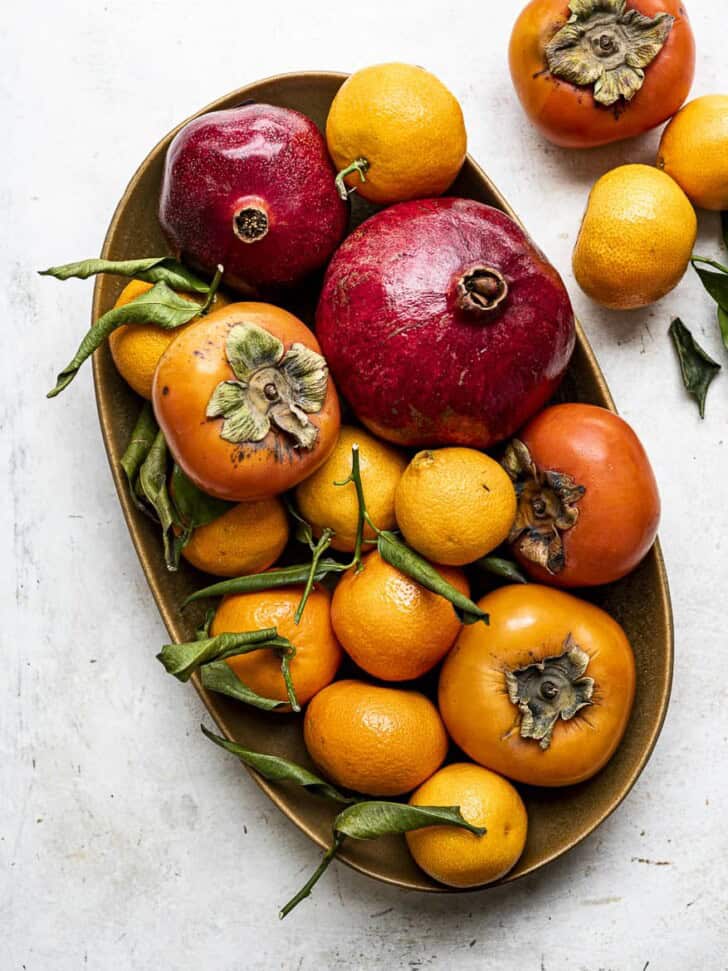 Persimmons, Mandarines, pomegranates and oranges in bowl