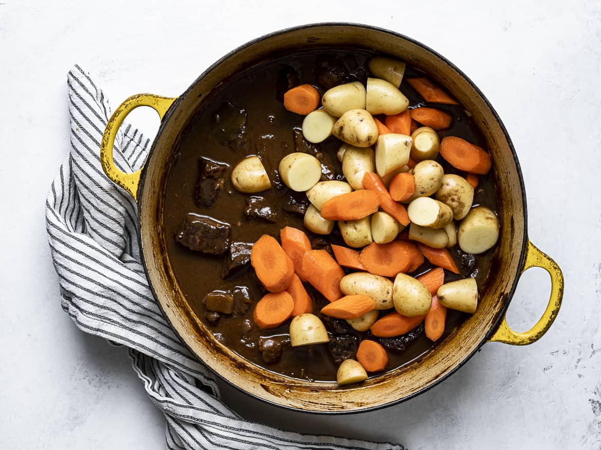 Adding potatoes and carrots to braised beef
