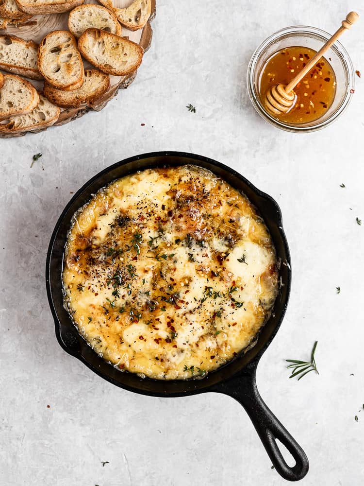 Baked Fontina with Herbs and Hot Honey in skillet served with crostini