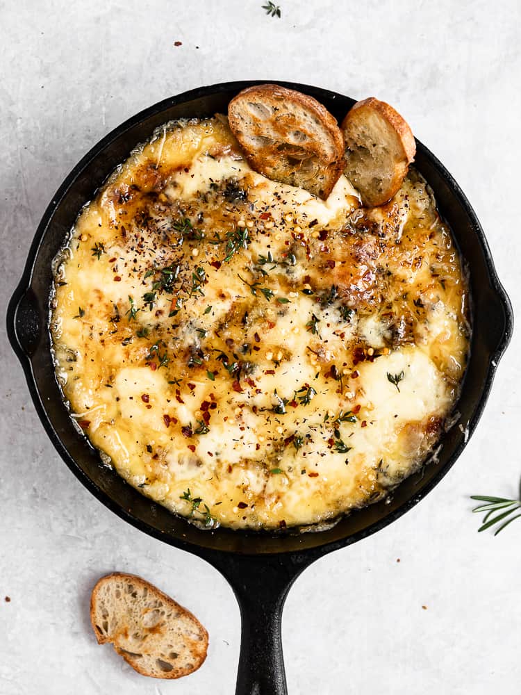 Baked Fontina with Herbs and Hot Honey in skillet served with crostini