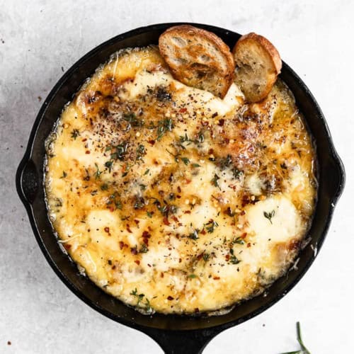 Baked Fontina with Herbs and Hot Honey in skillet served with crostini
