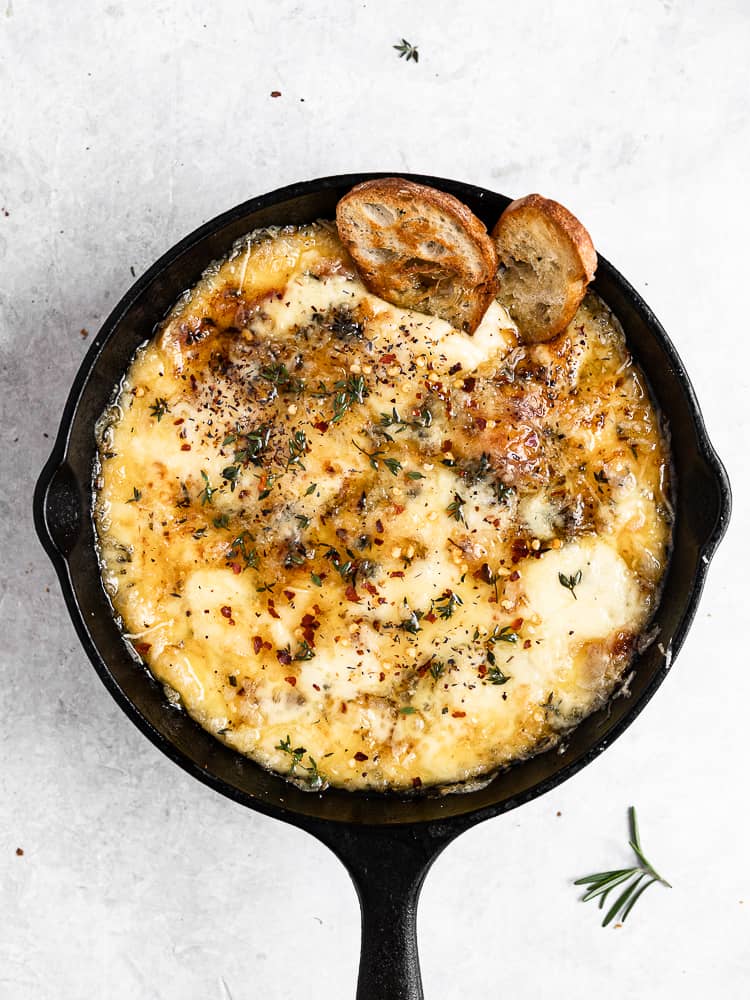 Baked Fontina with Herbs and Hot Honey in skillet served with crostini
