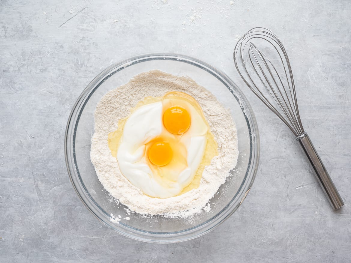 Adding eggs and yogurt to dry ingredient bowl