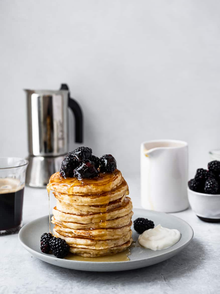 Pancake stack with blackberries and coffee in background