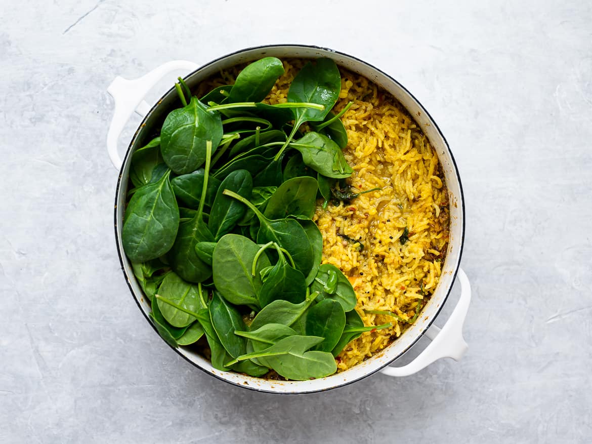 adding spinach to the cooked khichdi