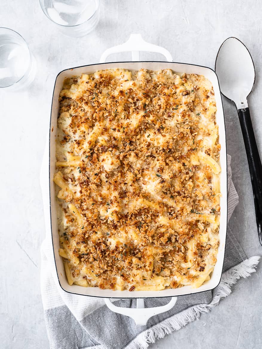 Baked Mac and Cheese with Cauliflower in casserole with large serving spoon