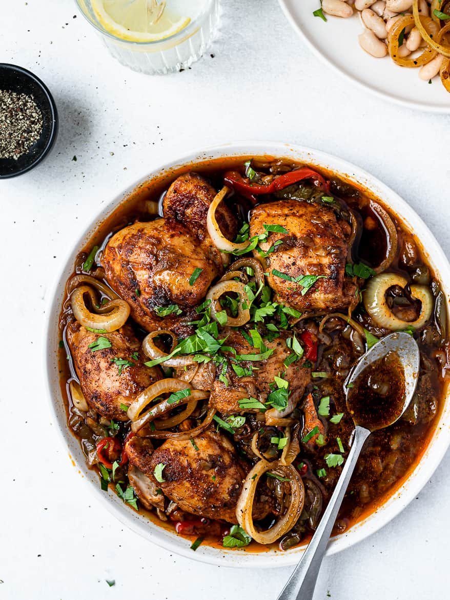 Instant Pot Chicken thighs on platter with spoon and beans on the side