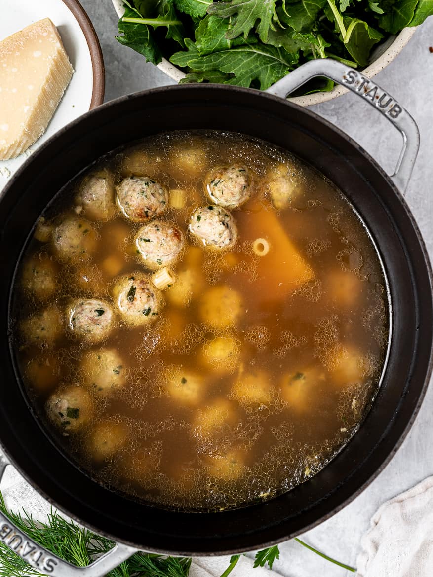 Meatballs and pasta cooking in broth.