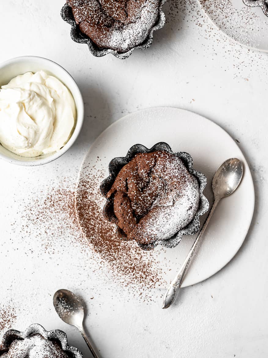 Individual Fallen Chocolate Soufflé Cakes with whipped mascarpone cream and dusting of powdered sugar