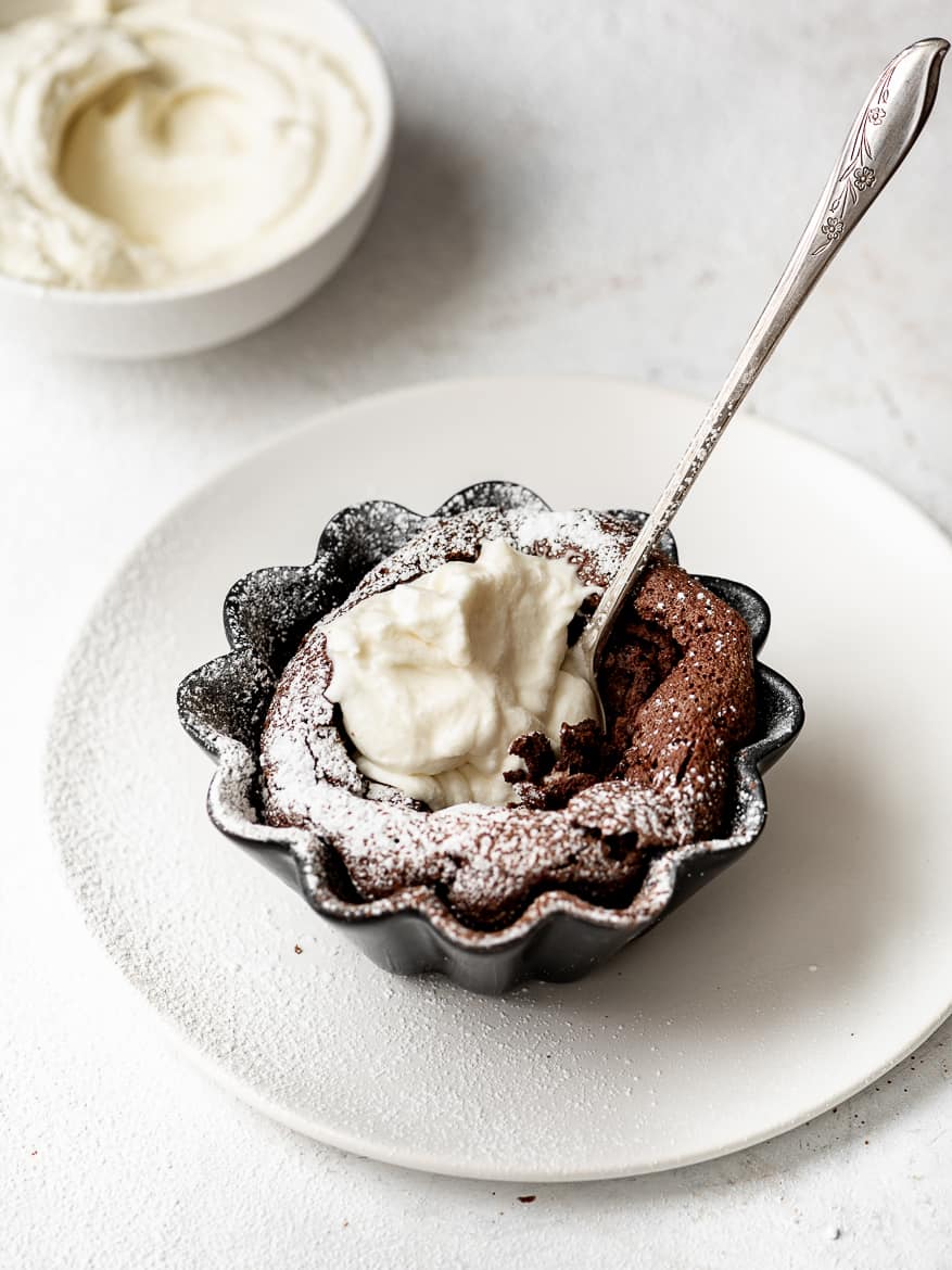 Close up of Individual Fallen Chocolate Soufflé Cakes with whipped mascarpone cream and dusting of powdered sugar