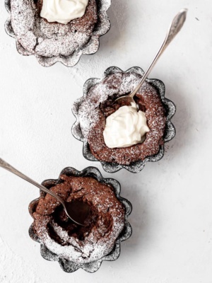 3 baked Fallen Chocolate Soufflé Cakes with whipped mascarpone cream and dusting of powdered sugar
