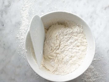 using dough scraper to remove dough from bowl