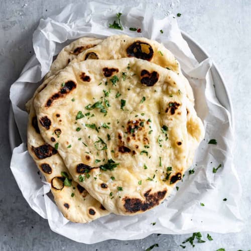 Homemade Naan with butter and cilantro on platter