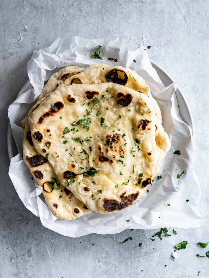 Homemade Naan with butter and cilantro on platter 