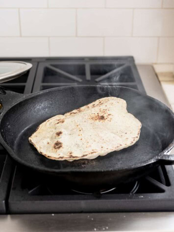 naan cooking in cast iron skillet