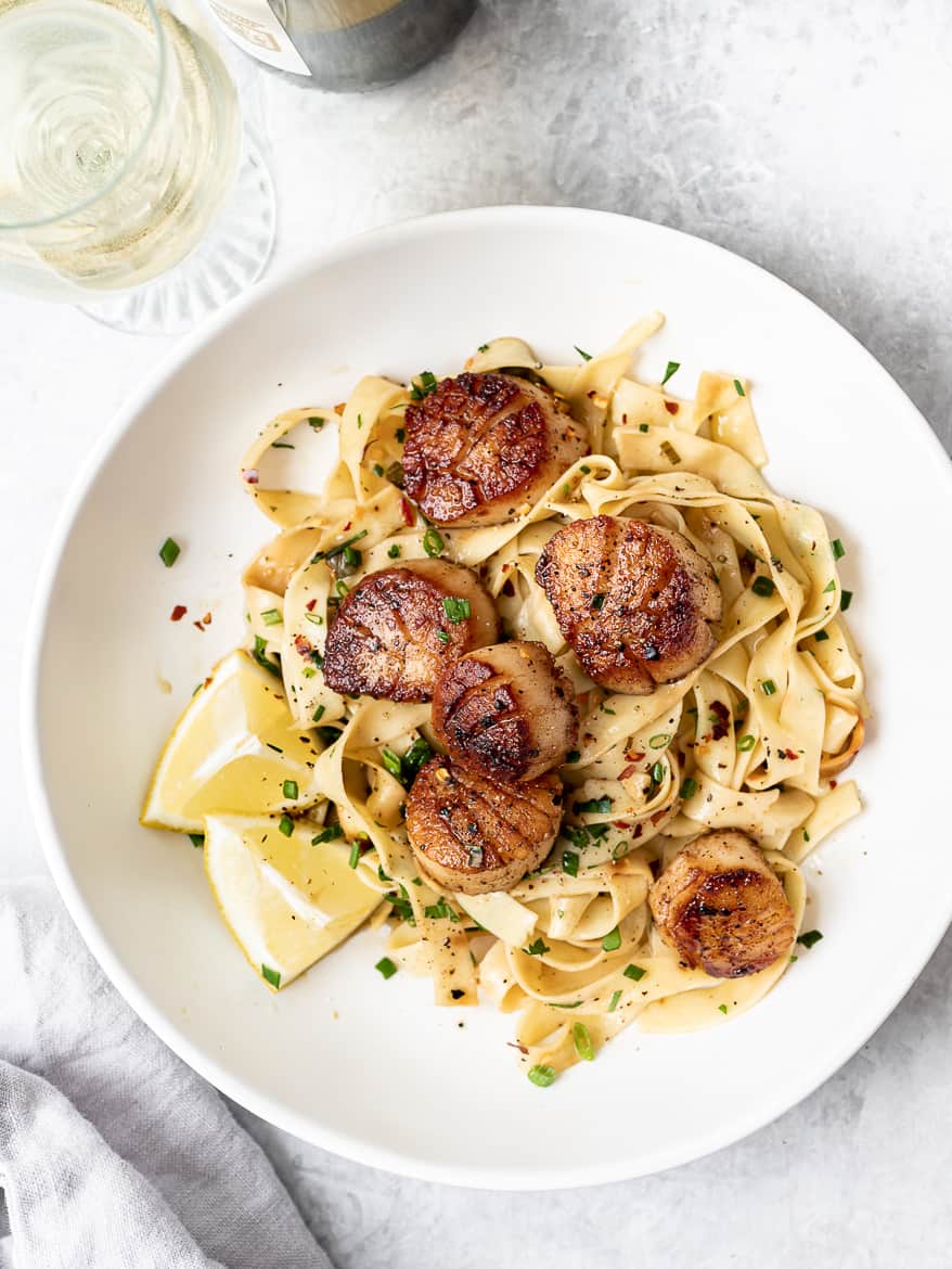 Pan Seared Scallops with Lemon Pasta served in bowl with glass of wine