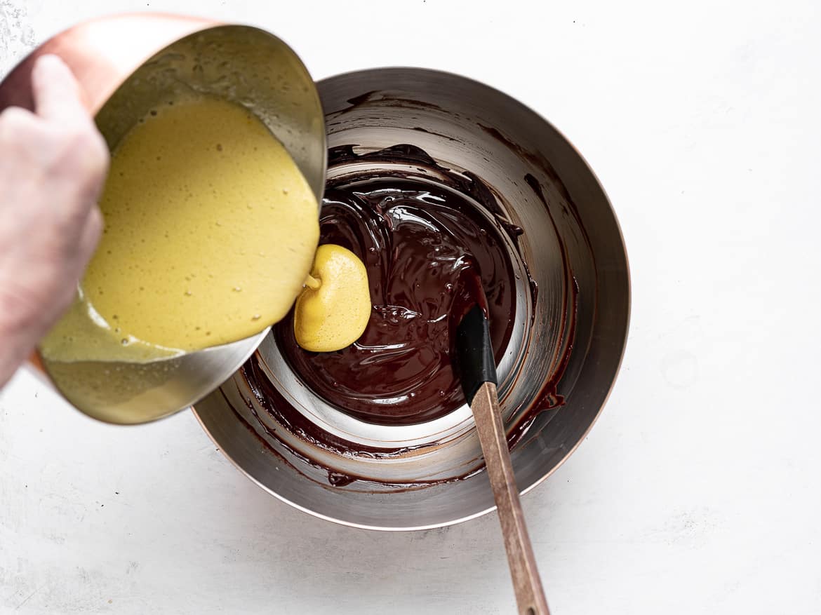 pouring egg yolk mixture into chocolate mixture