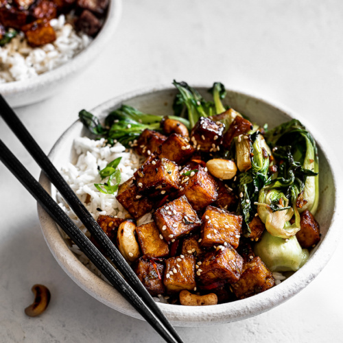 Side view of tofu and Bok Choy stir fry served in two white bowls with chopsticks.