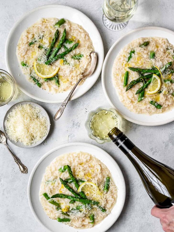 Lemon Asparagus Risotto served in shallow bowls with wine glasses