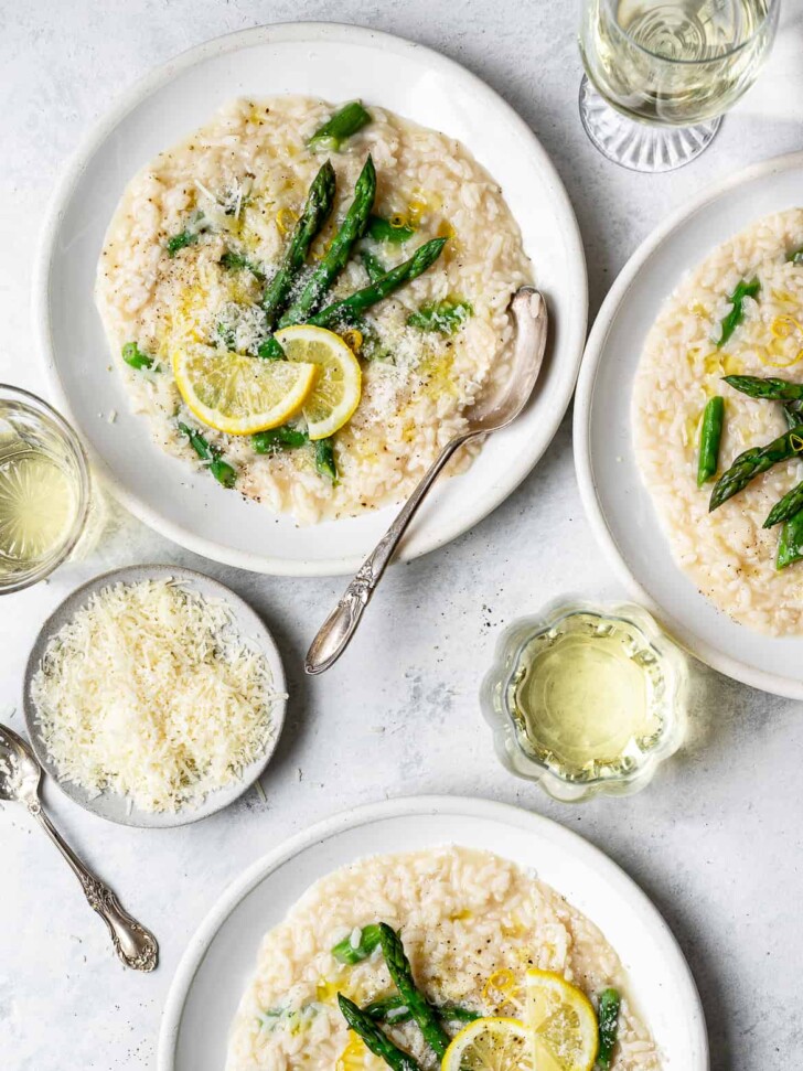 Lemon Asparagus Risotto served in shallow bowls with wine glasses
