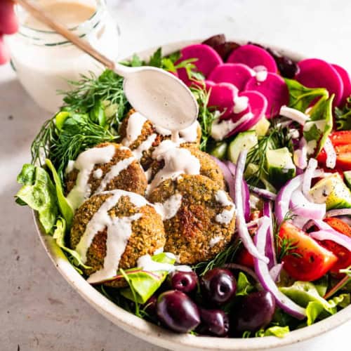 drizzling tahini sauce all over falafel bowl