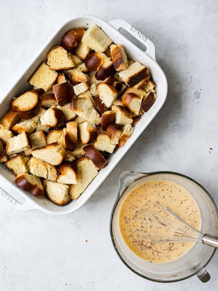 Cubed bread in baking dish with egg mixture in bowl