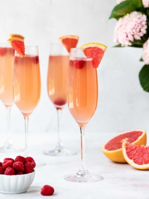 Grapefruit mimosa with raspberries served in tall champagne flutes
