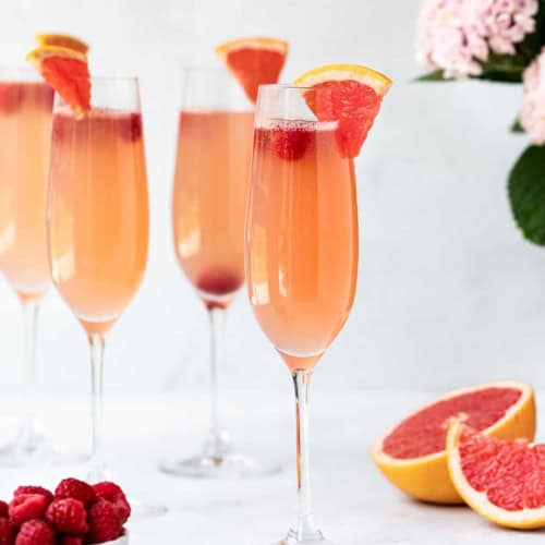Grapefruit mimosa with raspberries served in tall champagne flutes