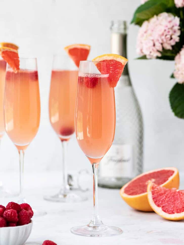 Grapefruit mimosa with raspberries served in tall champagne flutes