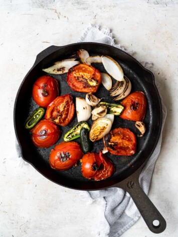 Charring tomatoes, onions, garlic and jalapeños in skillet