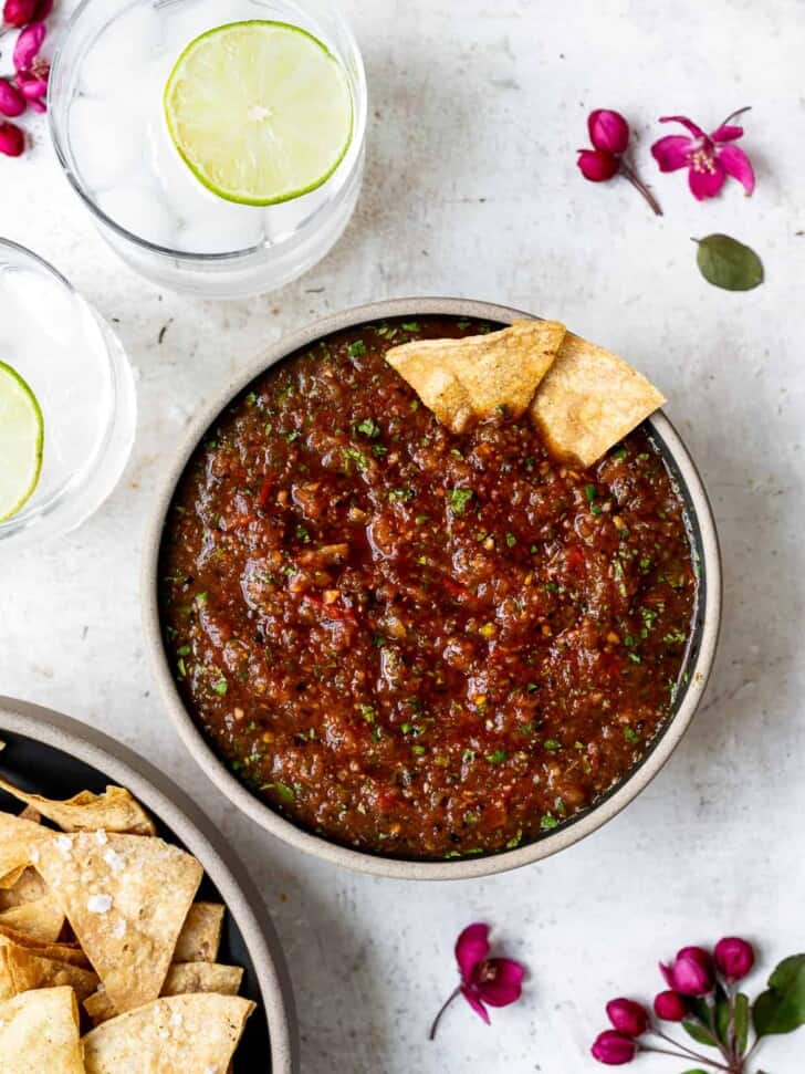 Charred Tomato Salsa in bowl with tortilla chips and drinks on the side