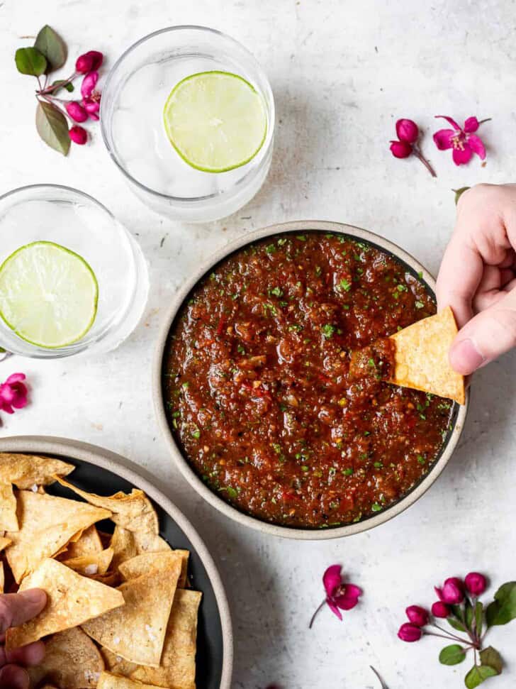 hands dipping into Charred tomato salsa bowl