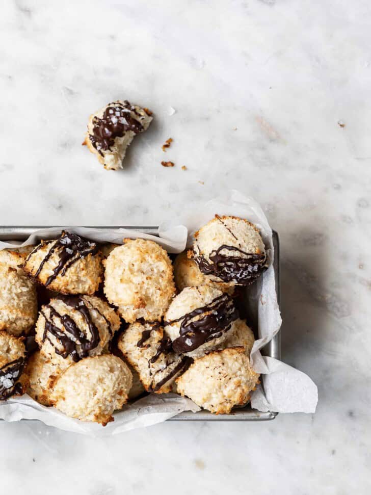 Baked coconut macaroons in loaf pan with one macaroon with a bite