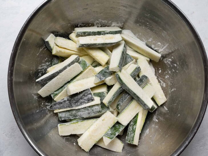 tossing zucchini sticks in flour