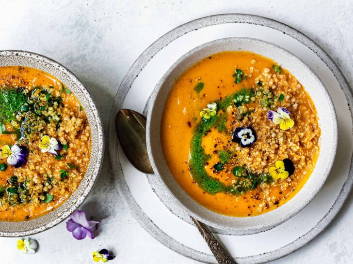 Creamy zucchini and tomato soup in bowl topped with quinoa and basil oil