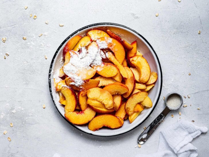 sliced peaches in bowl with cornstarch and sugar 