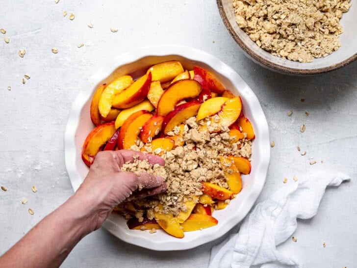 hand sprinkling topping over peaches 