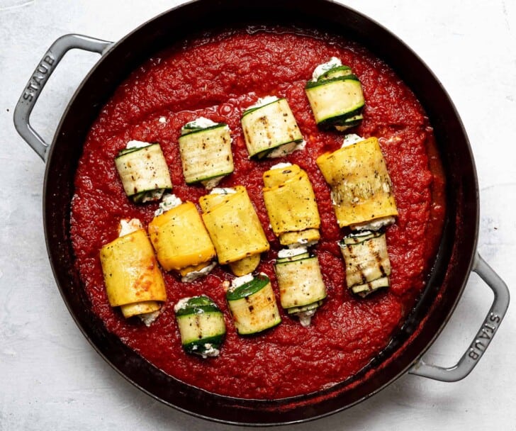 zucchini bundles placed in tomato sauce