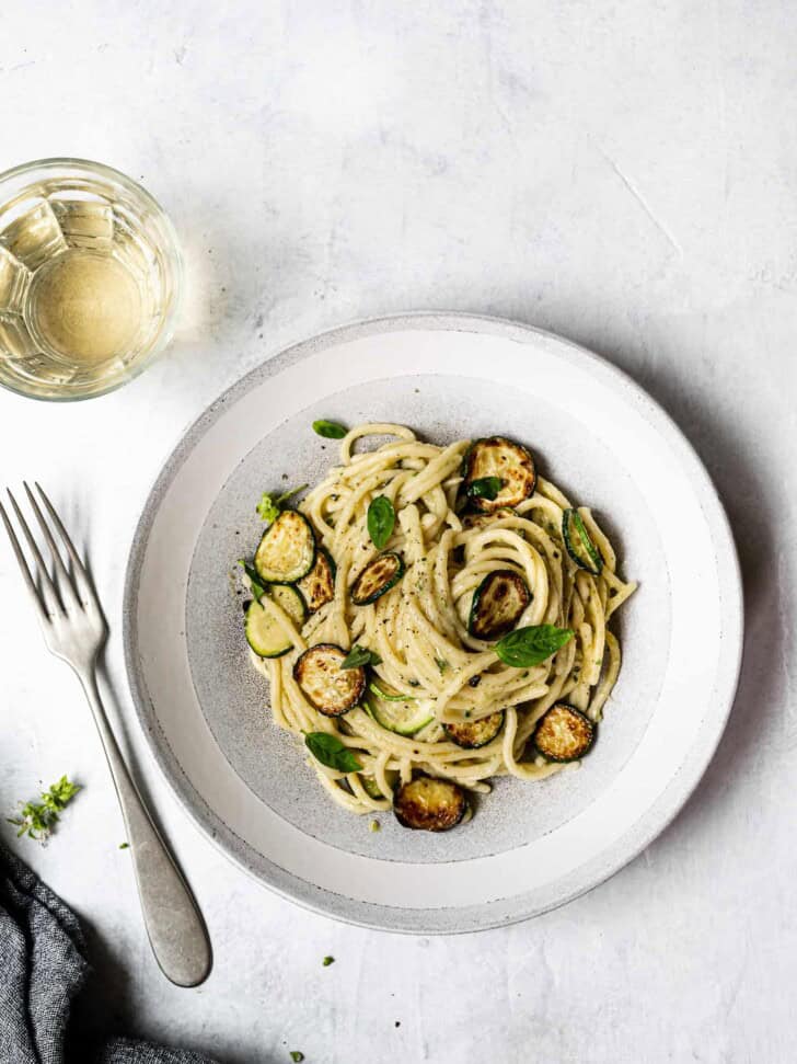 spaghetti alla Nerano served in a bowl with glass of wine