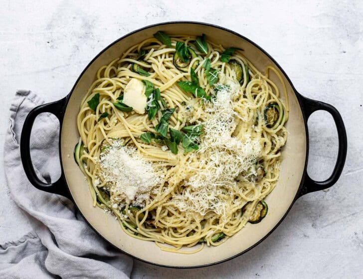 tossing pasta and zucchini with cheese