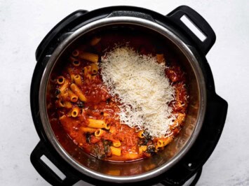 adding parmesan cheese to cooked pasta in pot