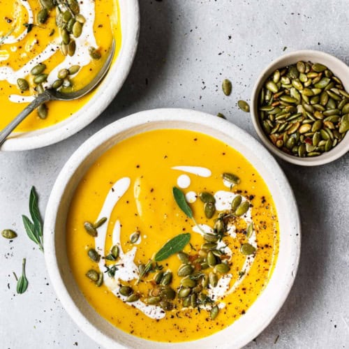 Butternut squash soup served in bowls and garnished with pepitas