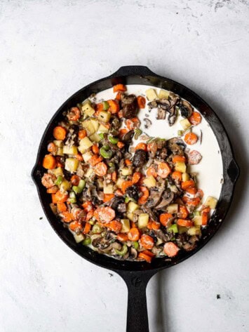 milk poured over vegetables in skillet