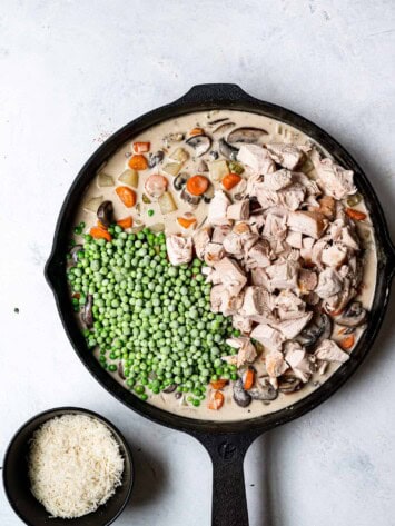 Adding chicken and frozen peas to the mixture in skillet