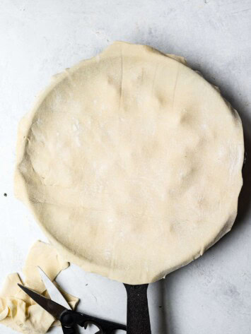 Puff pastry laid over skillet with filling