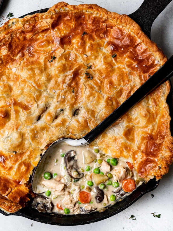 scooping out a piece of chicken pot pie from skillet