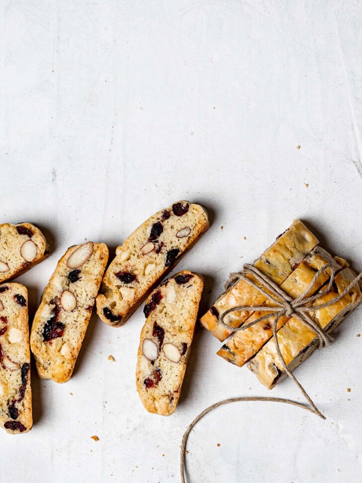 white chocolate cranberry biscotti lined on surface; some tied with ribbon