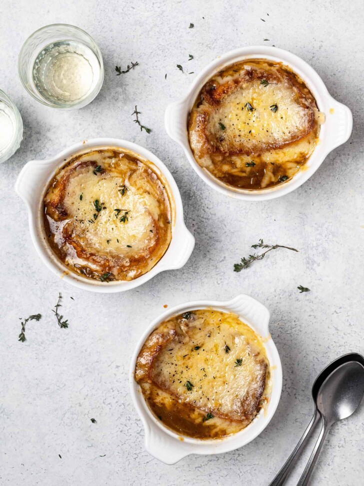 three bowls of French onion soup with cheesy topping 