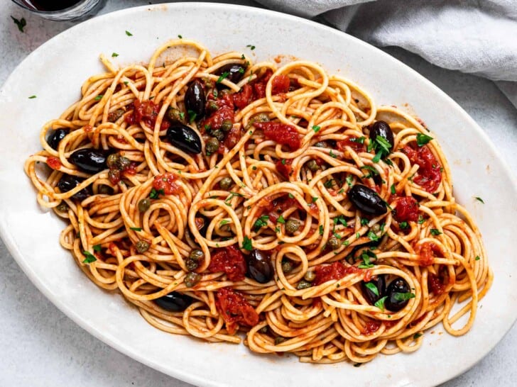 close up of pasta puttanesca served on platter