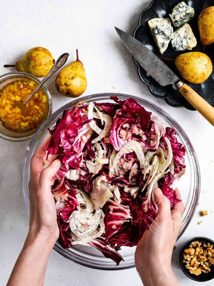 Hands tossing salad leaves in bowl 